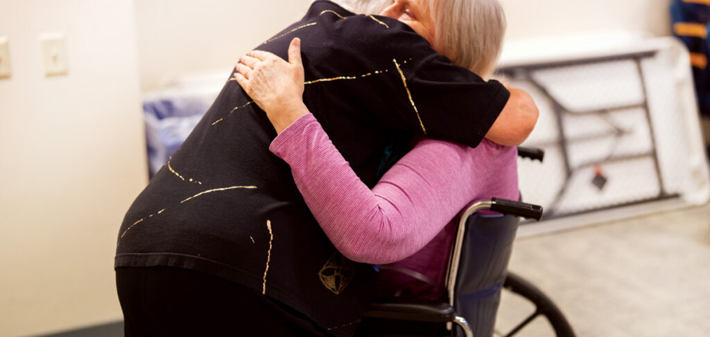 MaryAnn embraces a resident with compassion at Redeemer Health and Rehab, reflecting her legacy of love and service.
